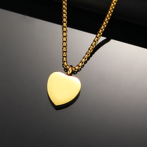 Polished gold heart perfume bottle necklace with box chain on a black reflective background