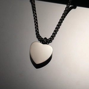 Macro shot of polished heart perfume bottle pendant on a black box chain link