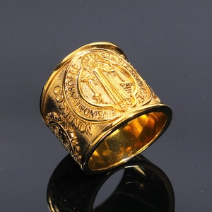 Macro detail of golden Saint Benedict medal ring with vintage embossed religious patterns