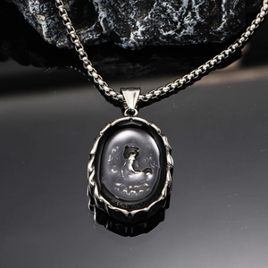 Macro detail of oval titanium steel elephant pendant with intricate engraved wave edges