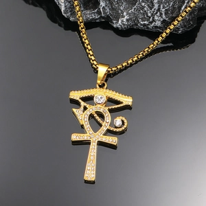 Goldene Ankh- und Horusauge-Halskette mit Strasssteinen auf strukturiertem Felsboden