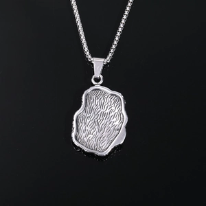 Macro shot of silver textured rectangular pendant and steel ball chain on black background