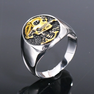 Dettaglio dell'anello con teschio dorato su superficie nera lucida e trama interna