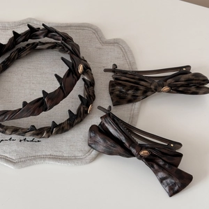 Close-up of tortoiseshell patterned bow hair clips and headband with golden love charms