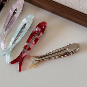 Close-up of marble-textured acetate fish hair clips with silver metal duckbill clips