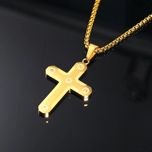 Gros plan du pendentif croix dorée serti de zircons sur une surface noire réfléchissante