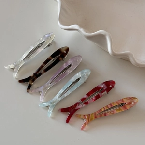 Set of 6 colorful acetate fish hair clips with rhinestones on a white shell tray