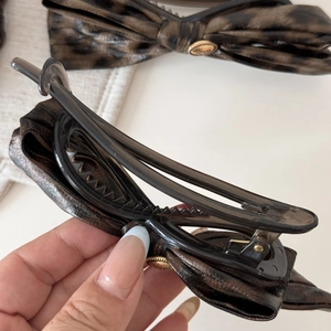 Close-up of leopard print bow hair clip with gold metal buckle and black duckbill clip