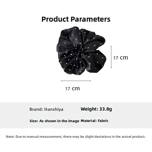 Detailed view of large black satin scrunchie with white polka dots and fashion label