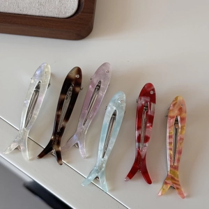 Detailed view of colorful acetate fish hair clips with sparkling rhinestones and engravings