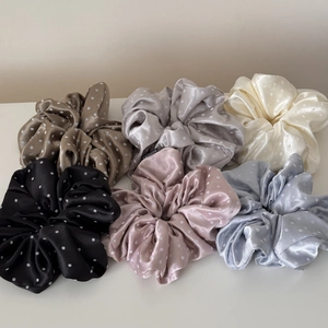 Detailed set of six polka dot satin scrunchies in various colors on flat surface