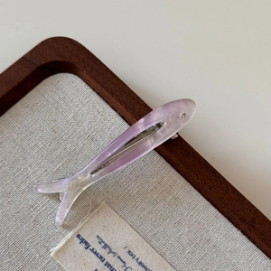 Detailed view of the fish-shaped purple acetate hair clip with glitter on canvas background