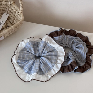 Detail showing oversized blue plaid and striped scrunchies with wavy ruffle edges