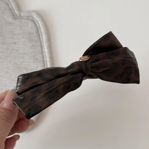 Detailed macro view of dark leopard bow hair clip with a gold LOVE engraved buckle