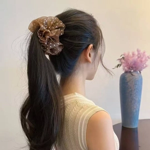 Detail view of a brown polka dot mesh scrunchie holding a ponytail for a French elegant look
