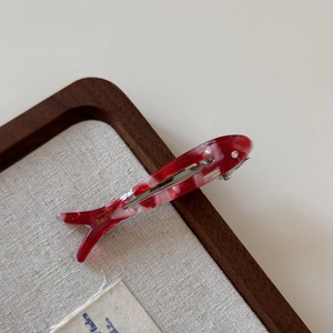 Detail of red marble acetate fish hair clip with Sunshine handmade gold lettering