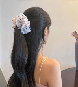 Detail of elegant white polka dot chiffon scrunchie shown on a woman long dark hair