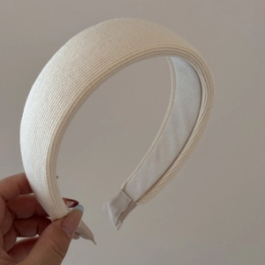 Dettaglio del cerchietto in maglia crema con trama a costine verticali e fodera interna