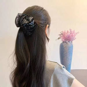 Close-up of a large black mesh scrunchie with white polka dots on long dark hair