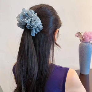 Detail of light blue polka dot tulle scrunchie styled on a woman's hair ponytail