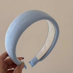 Primo piano del cerchietto in maglia azzurro che mostra la trama spessa e l'interno