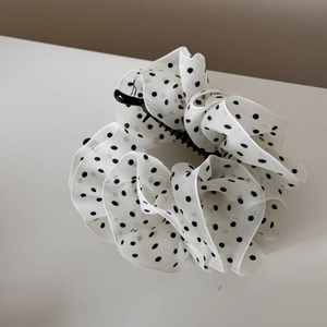 Detail of elegant white polka dot organza fabric on a large black hair claw clip accessory