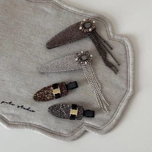 Elegant rhinestone tassel hair clips and crystal snap clips set on beige linen background