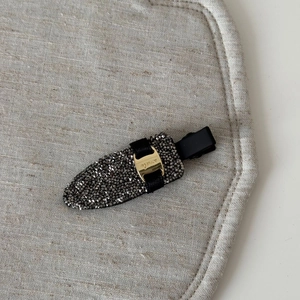 Detailed macro view of a rhinestone hair clip with golden metal smile engraving