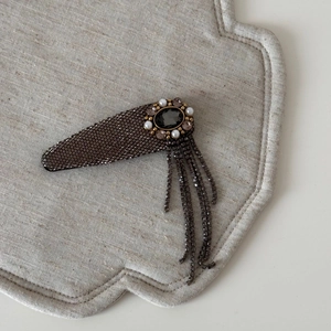 Close-up of vintage tassel hair clip with gray rhinestones and oval center stone