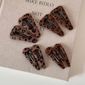 Close-up of vintage leopard print hair clips with matte texture on linen background