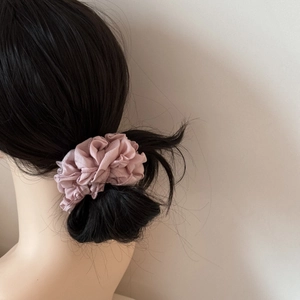 Chouchou en mousseline rose sur un chignon avec des textures plissées et un style élégant