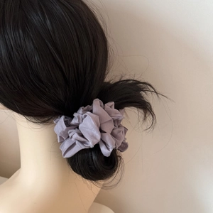 Gros plan d'un chouchou en tissu violet avec bords festonnés délicats sur une queue de cheval