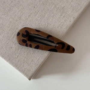 Detailed close-up of leopard print fabric BB hair clip with black metal inner clasp
