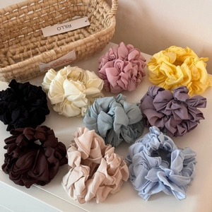 Gros plan de 9 chouchous en tissu plissé aux couleurs unies élégantes et variées