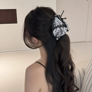 Detailed shot of a satin polka dot hair claw clip with lace and pearl on long wavy hair