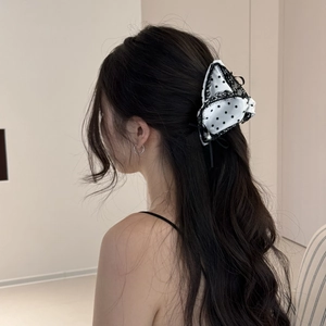 Polka dot satin bow hair claw with lace trim and pearl detail shown on hair