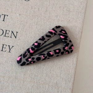 Dettaglio macro della clip per capelli BB a triangolo con stampa leopardata e neon