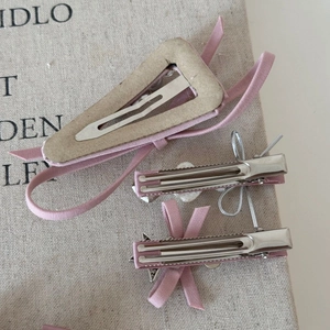 Détail de barrettes à cheveux à nœuds roses avec perles et strass sur fond de tissu beige