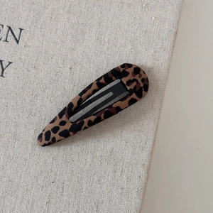 Primo piano del fermaglio per capelli leopardato su uno sfondo di lino testurizzato
