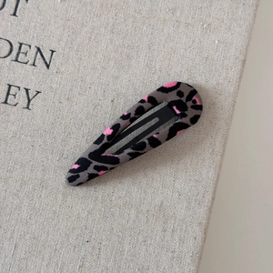 Dettaglio del fermaglio per capelli BB in tessuto leopardato su sfondo di tela beige