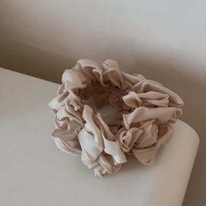 Détail d'un chouchou plissé beige montrant la texture du tissu et les coutures fines
