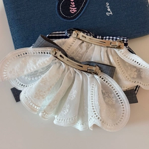 Close-up of white lace hair clip pair with floral embroidery and silver metal spring clip