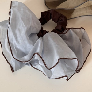 Close-up of light blue tulle scrunchie with dark brown piping and pleated texture
