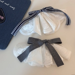 Detailed close-up of intricate white floral lace hair clips with plaid and grey ribbon bows