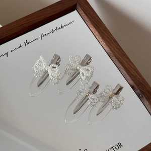 Detailed view of handmade pearl bow hair clips with crystal beads on a mirror display