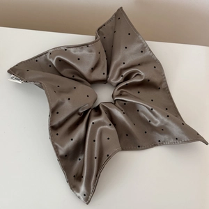 Detail of satin coffee-colored hair scrunchie with black polka dots and fine stitching