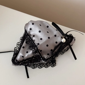 Detail of satin hair clip with black polka dots, lace edges, ribbon bow, and white pearl