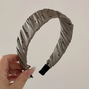 Detail of ruched taupe satin headband featuring black polka dots and soft texture