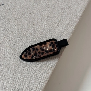 Close-up of vintage leopard print hair clip with black duckbill base on gray fabric