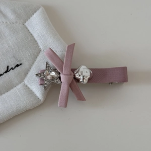 Détail de la pince à cheveux noeud rose avec strass en forme d'étoile et détails argentés